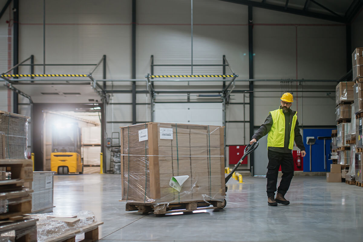 worker handling a pallet jack full of inventory